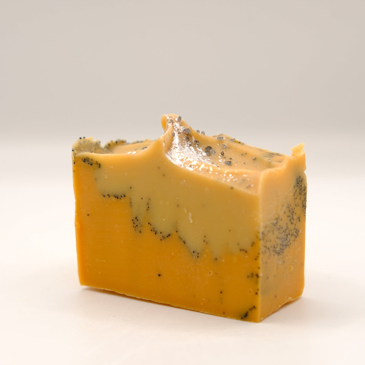 Block of yellow soap bar with specks on a white background