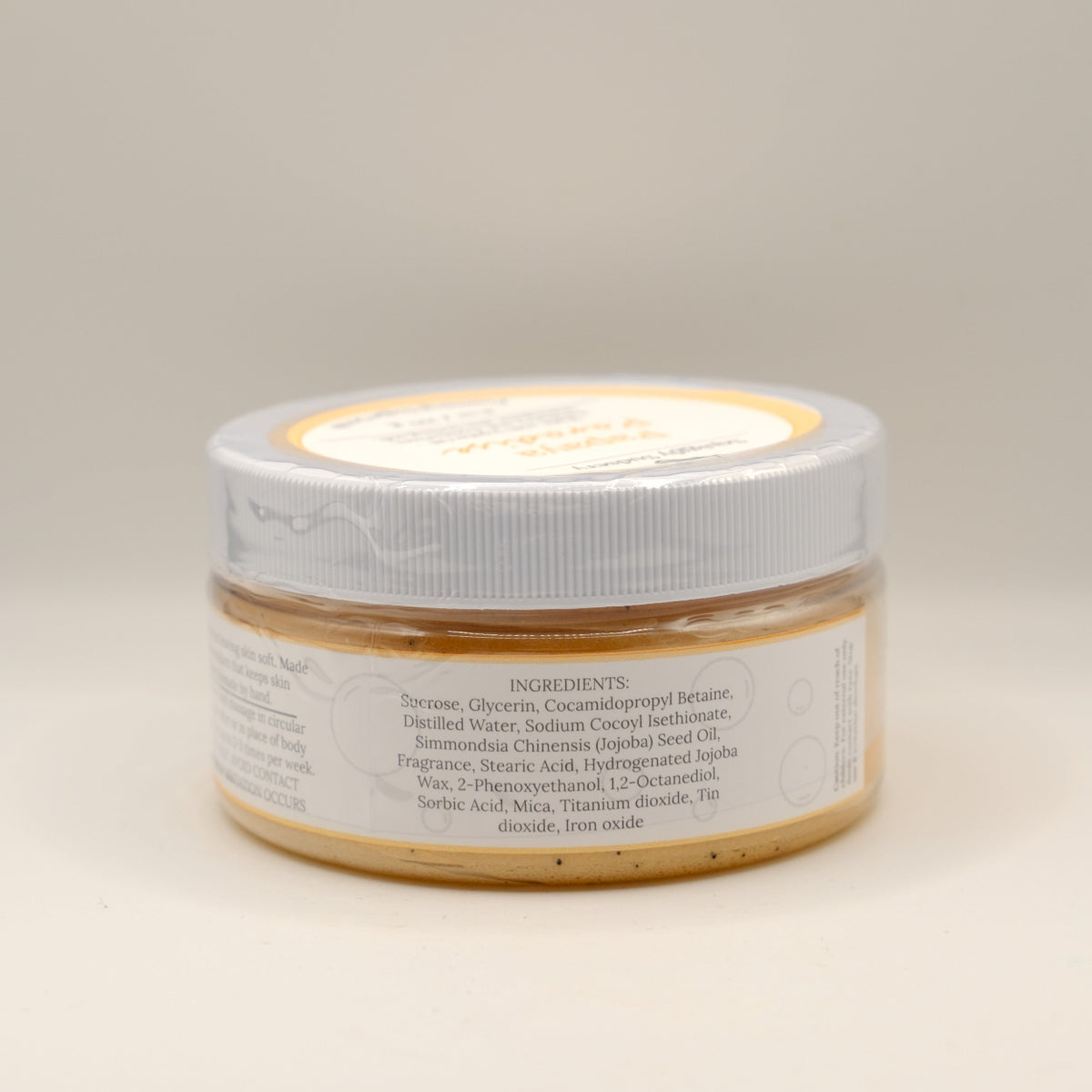 Jar of sugar scrub with a white lid on a beige background