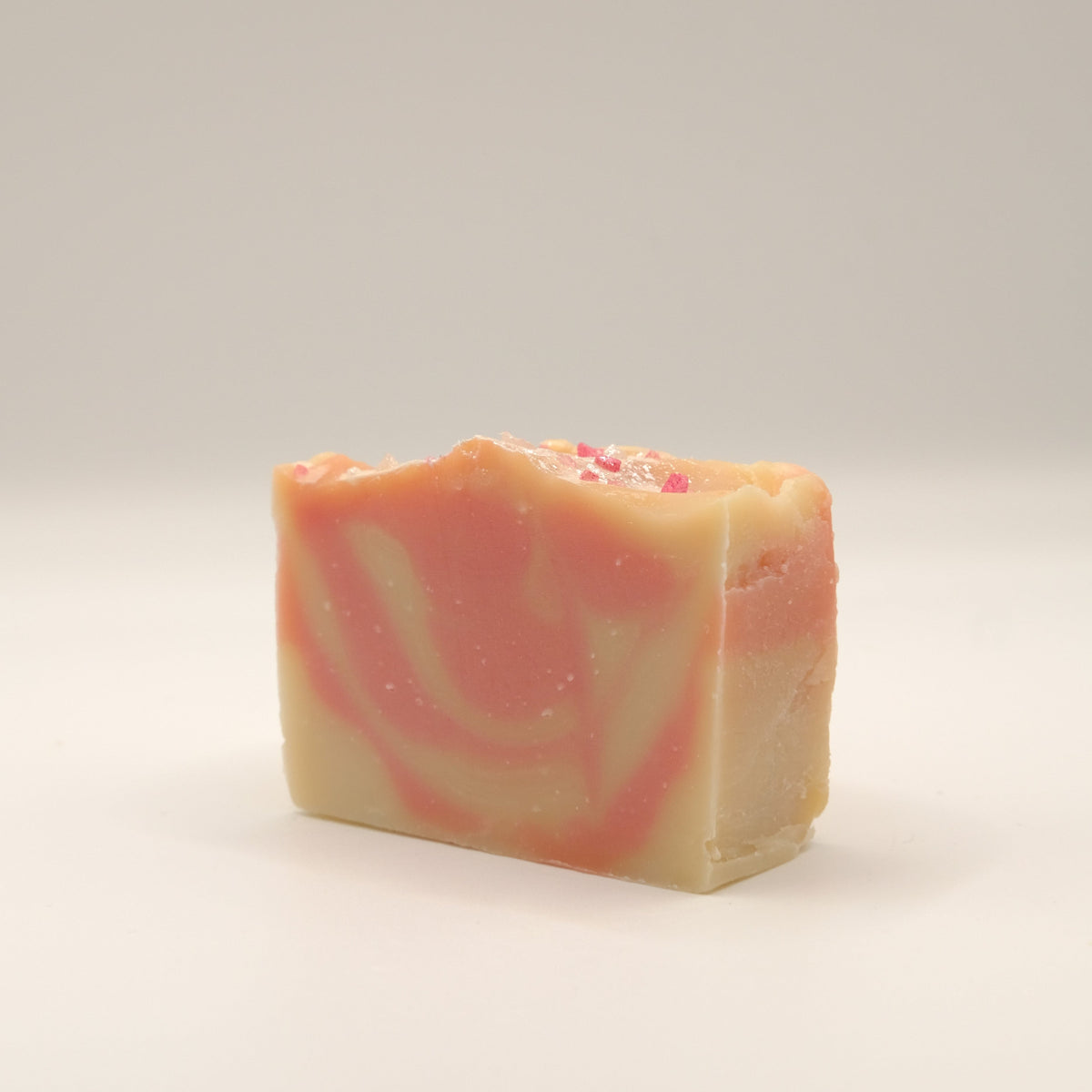 Bar of soap with red and beige swirls on a light background