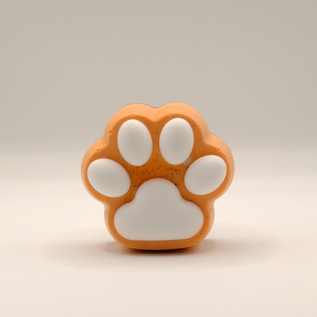 Orange and white paw-shaped soap bar on a beige background