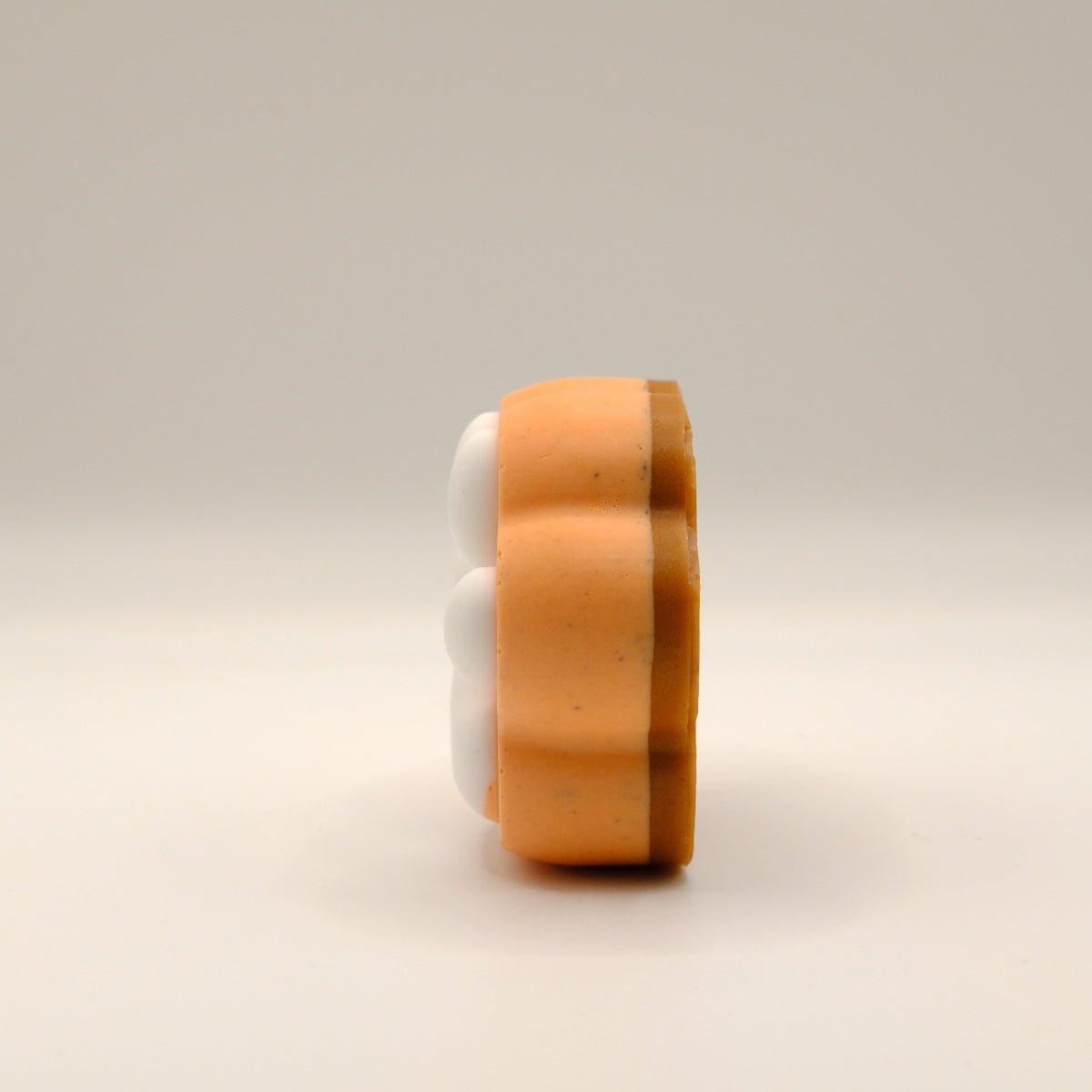 Orange, brown and white paw-shaped soap bar on a beige background