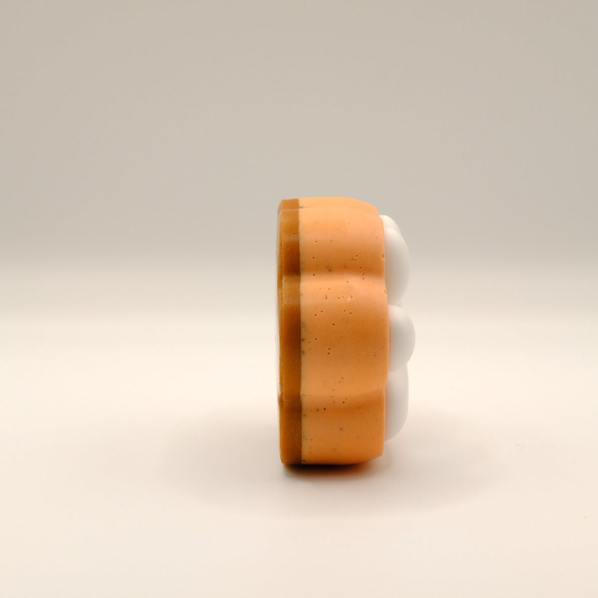 Orange, brown and white paw-shaped soap bar on a beige background