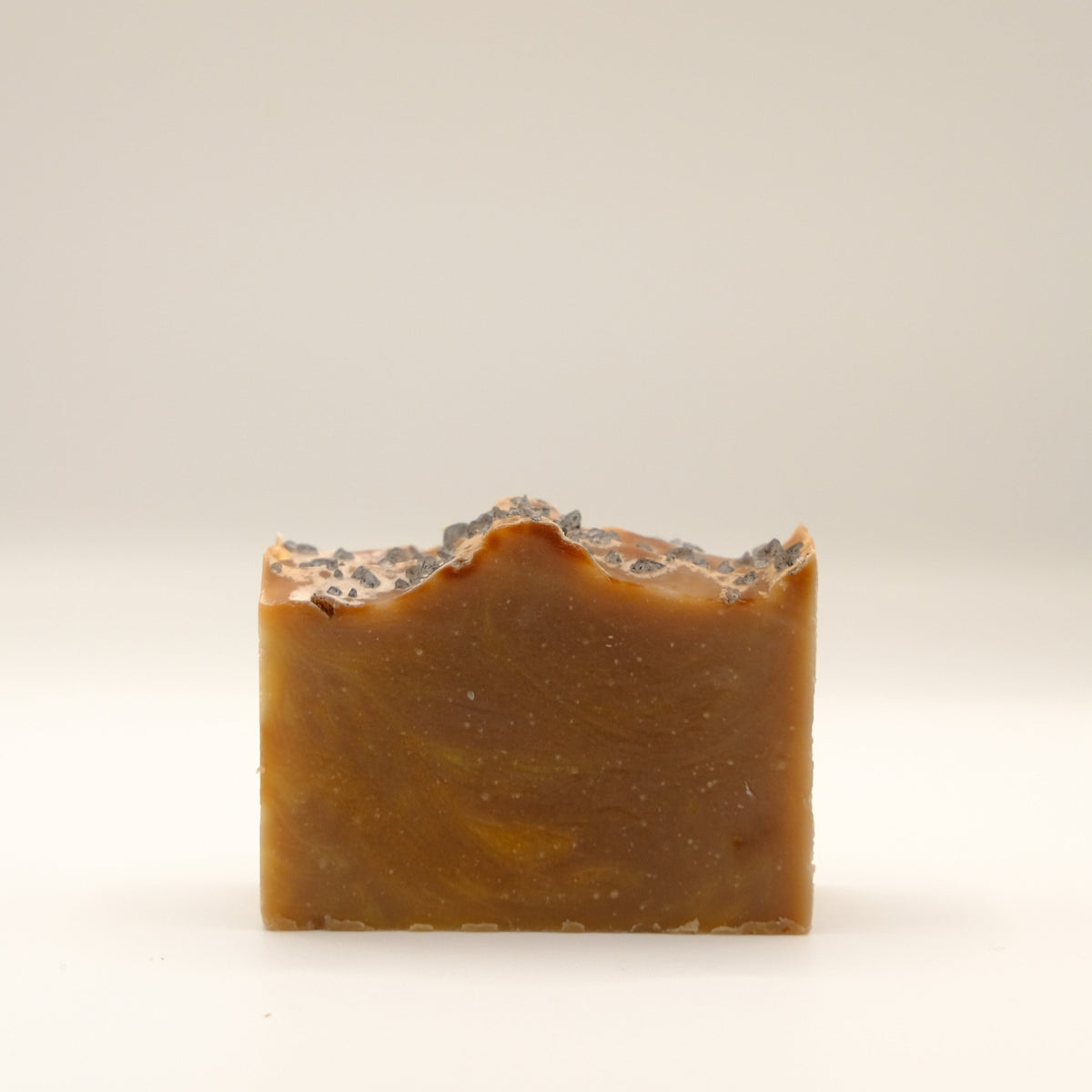 Brown bar of soap with a textured surface on a light beige background