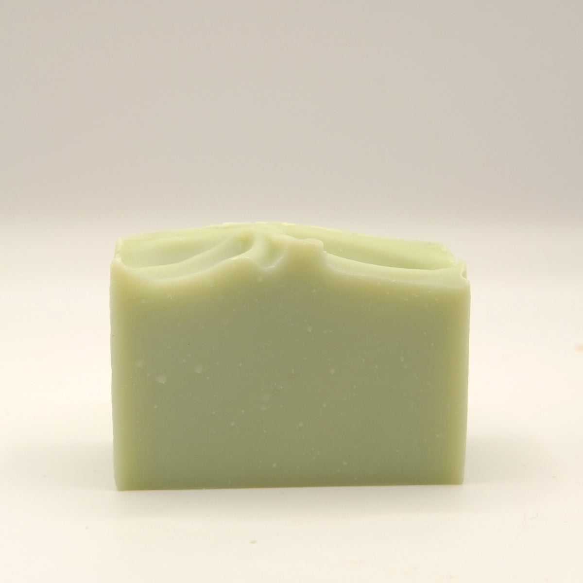 Green bar of soap with a textured top on a light background