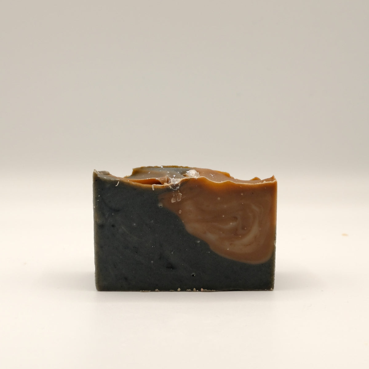 Two-tone soap bar with black and brown colors on a light gray background