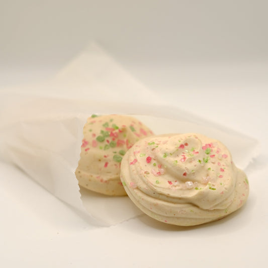 Two sugar cookies made out of soap with colorful sprinkles on a white surface