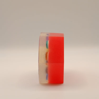 Hexagonal red soap bar with colorful eye-shaped designs on a beige background