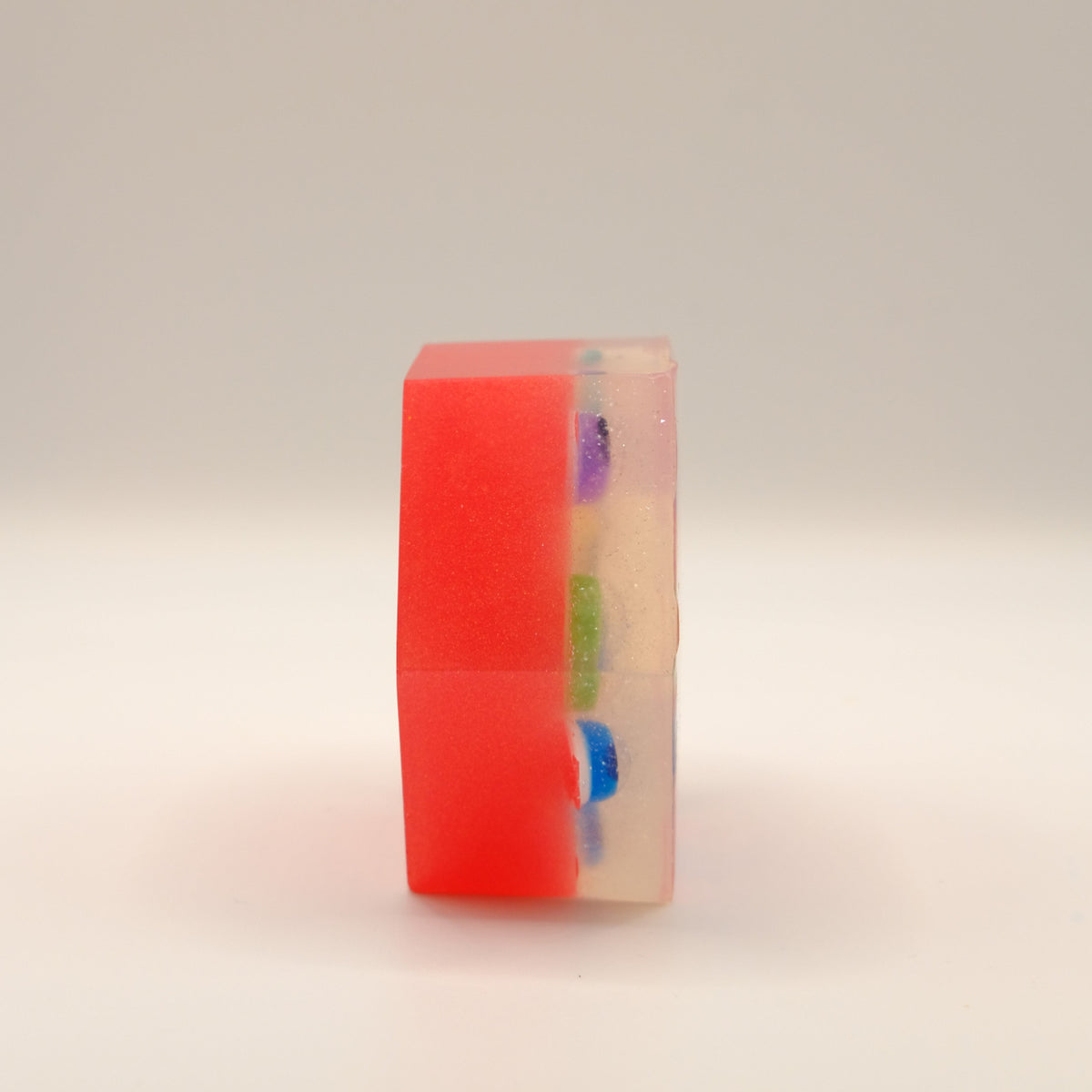 Red hexagonal soap bar with colorful embeds on a light background