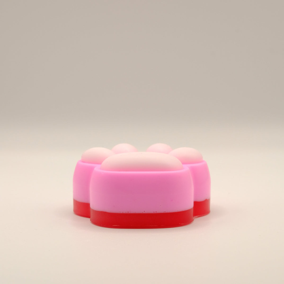 Pink, white and red soap bar with a paw print design on a beige background