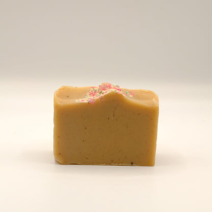 Light brown bar of soap with pink specks on a light background