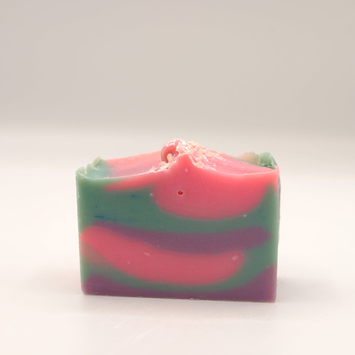 Colorful soap bar with pink, purple and blue swirls on a white background