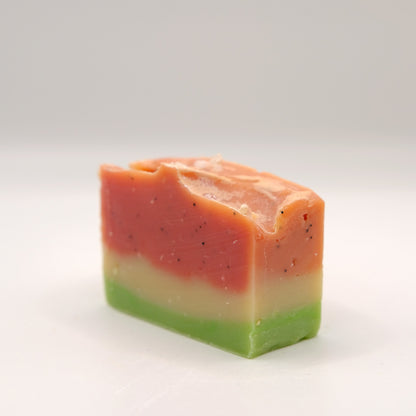 Three-layered soap bar with pink, white, and green colors on a light gray background