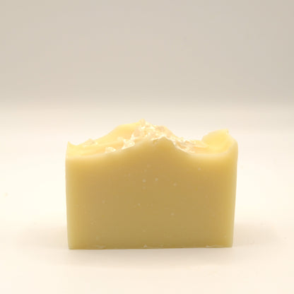 Yellow bar of soap with a textured top on a light beige background